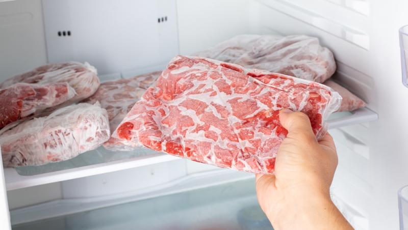 mână care scoate o bucată de carne de la congelator
