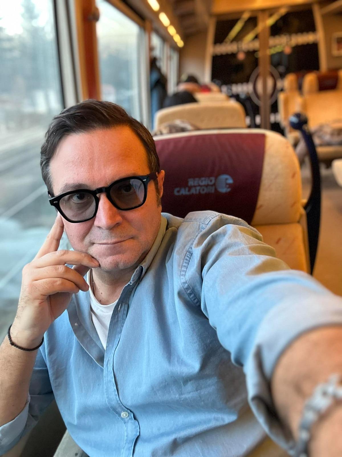 Daniel Buzdugan îmbrăcat cu o cămașă din denim, călătorind cu trenul