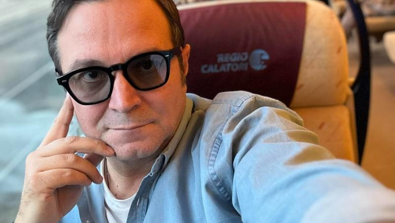 Daniel Buzdugan îmbrăcat cu o cămașă din denim, călătorind cu trenul