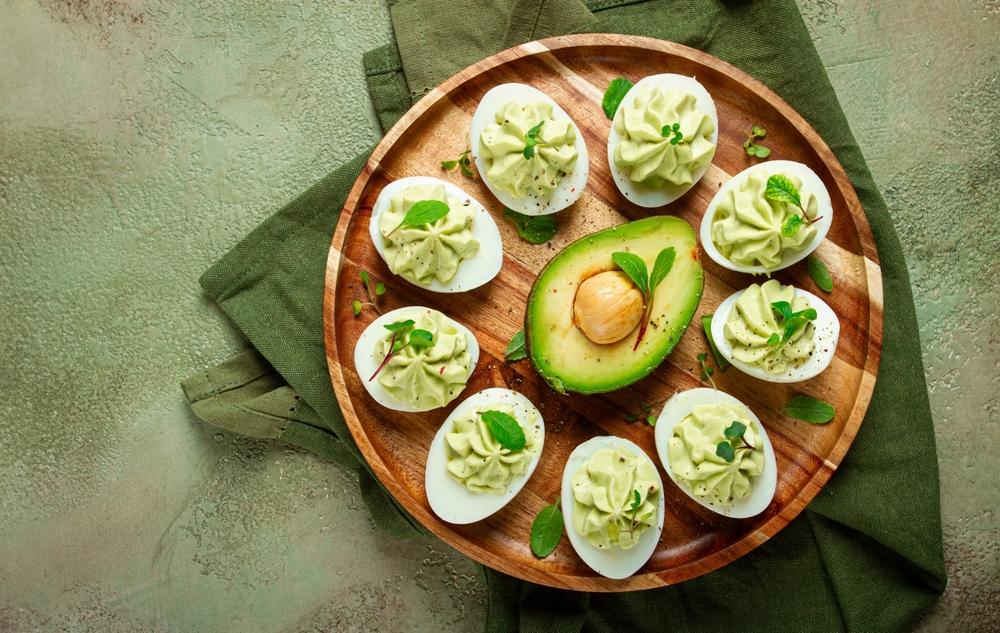 ouă umplute cu avocado pe un platou de lemn