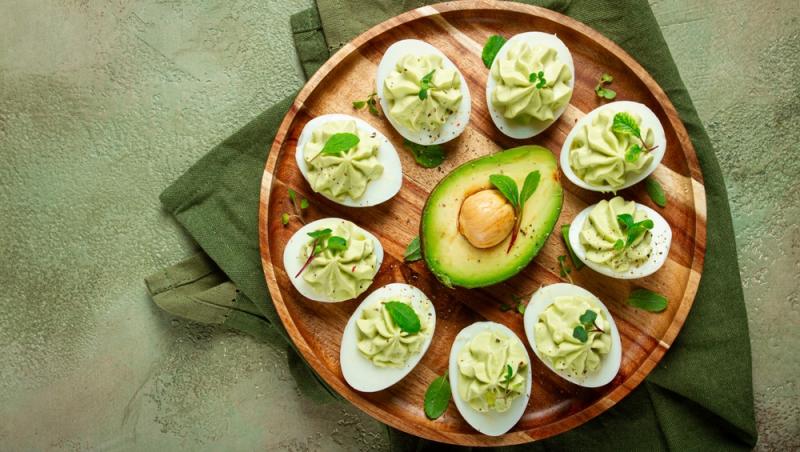 ouă umplute cu avocado pe un platou de lemn