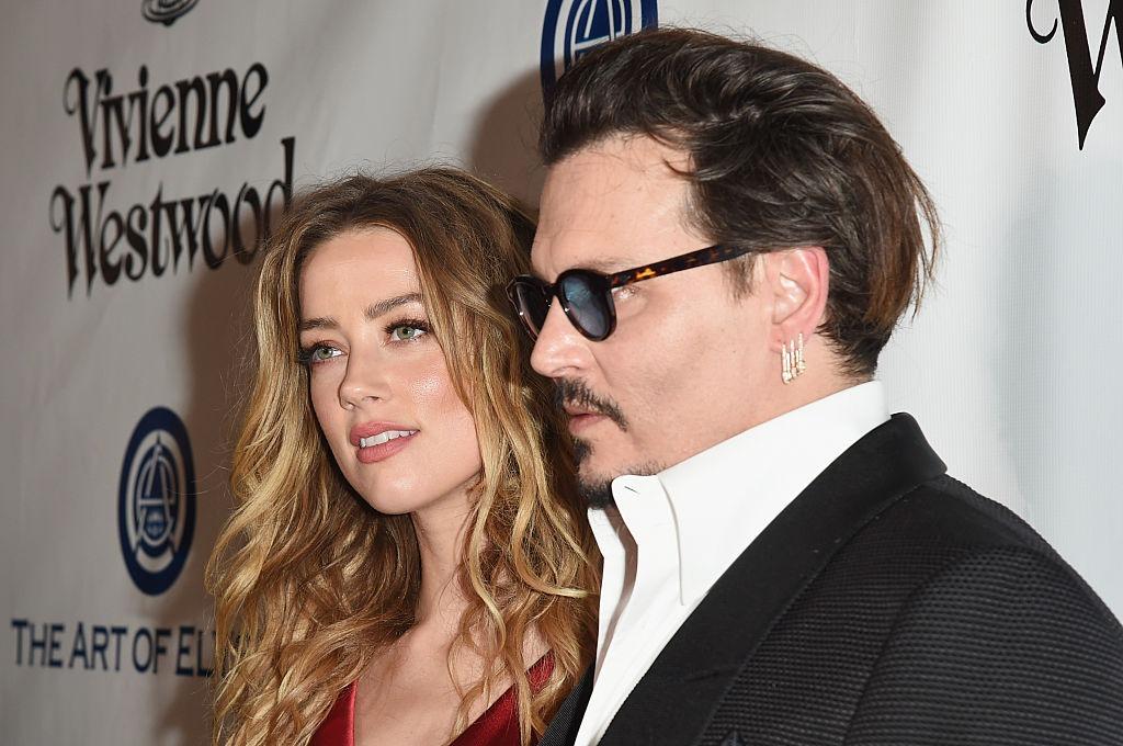 Amber Heard îmbrăcată într-o rochie roșie, alături de Johnny Depp, îmbrăcat cu un costum negru