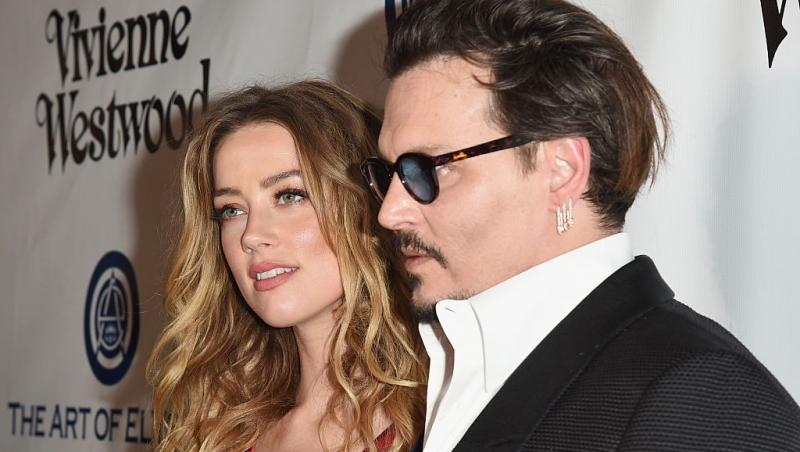 Amber Heard îmbrăcată într-o rochie roșie, alături de Johnny Depp, îmbrăcat cu un costum negru