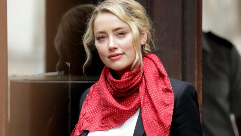Amber Heard îmbrăcată cu un sacou negru accesorizat cu o eșarfă roșie cu buline albe