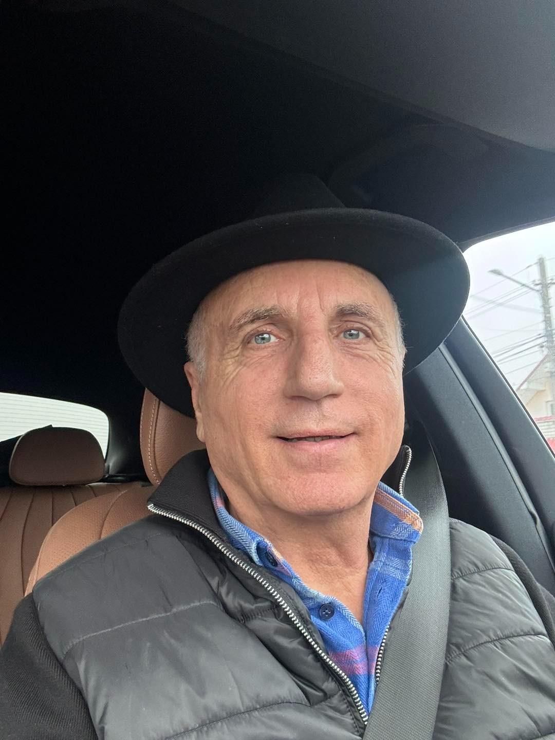 Constantin Enceanu îmbrăcat cu o geacă gri, stând într-o mașină