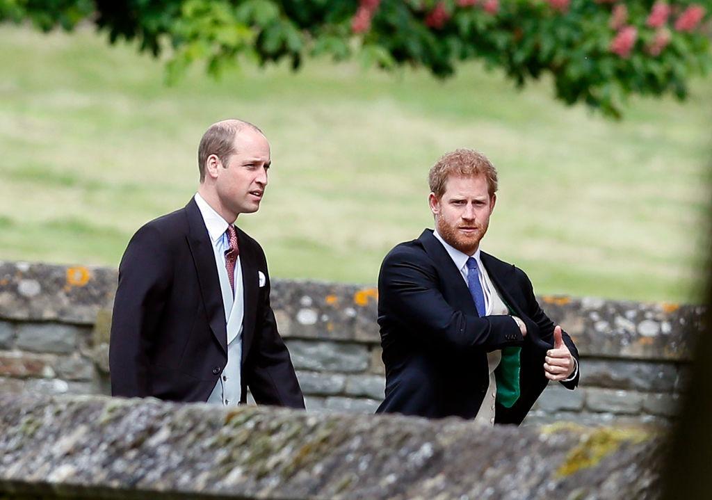 Prințul Harry și Prințul William îmbrăcați în costume negre, mergând