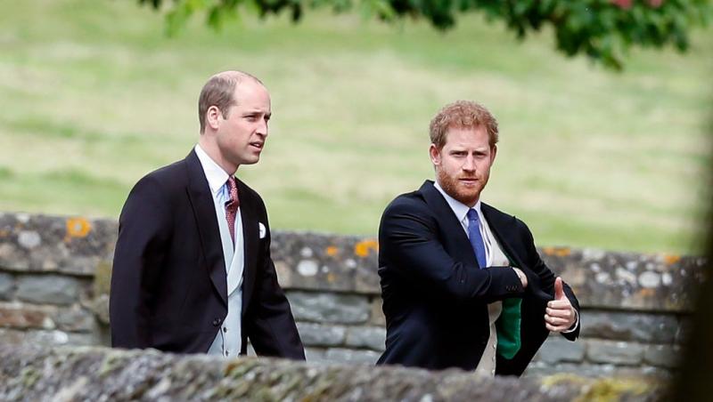 Prințul Harry și Prințul William îmbrăcați în costume negre, mergând