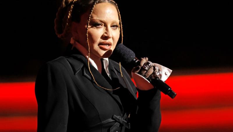 Madonna îmbrăcată într-o ținută neagră vorbind la microfon