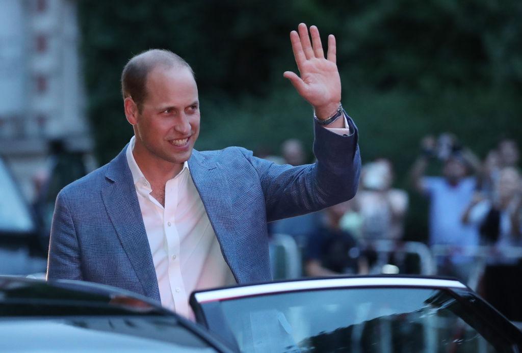 Prințul William îmbrăcat într-un costum bleumarin, salutând lumea