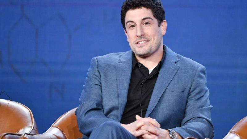 Jason Biggs îmbrăcat cu un costum bleumarin peste o cămașă neagră