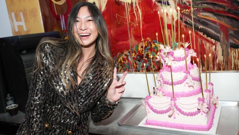 Lucy Guo îmbrăcată într-o ținută strălucitoare, pozând lângă un tort roz