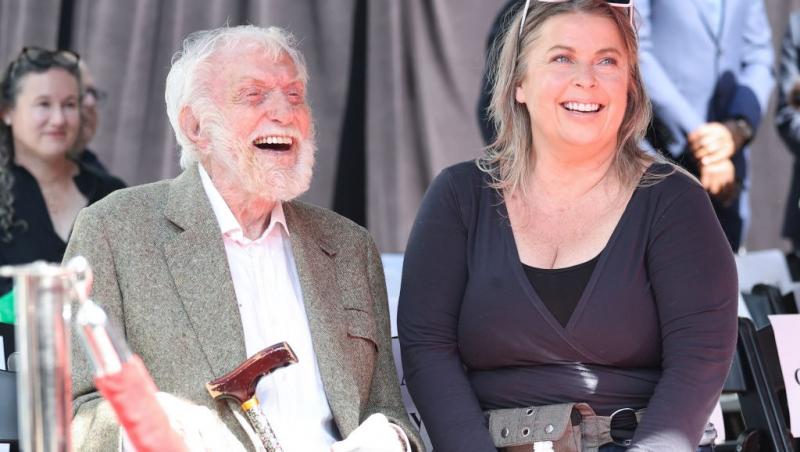 Dick Van Dyke îmbrăcat într-un costum gri, alături de soția lui, îmbrăcată într-o ținută bleumarin