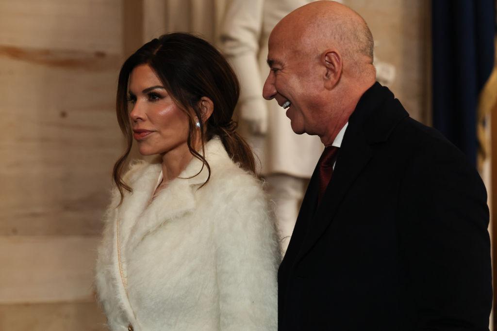 Jeff Bezos îmbrăcat în negru, alături de Lauren Sanchez, îmbrăcată în alb