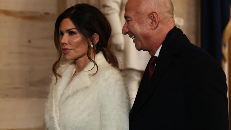 Jeff Bezos îmbrăcat în negru, alături de Lauren Sanchez, îmbrăcată în alb