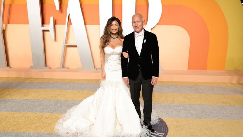 Jeff Bezos îmbrăcat în negru, alături de Lauren Sanchez, îmbrăcată într-o rochie albă