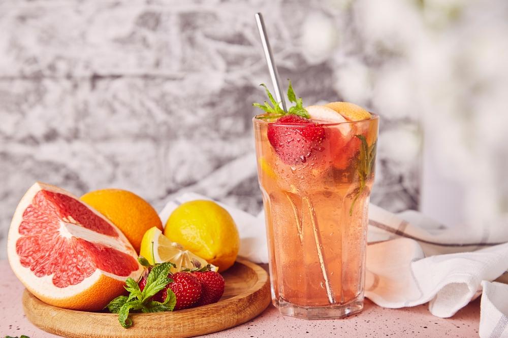 pahar cu limonadă, bucăți de grapefruit și felii de lămâi