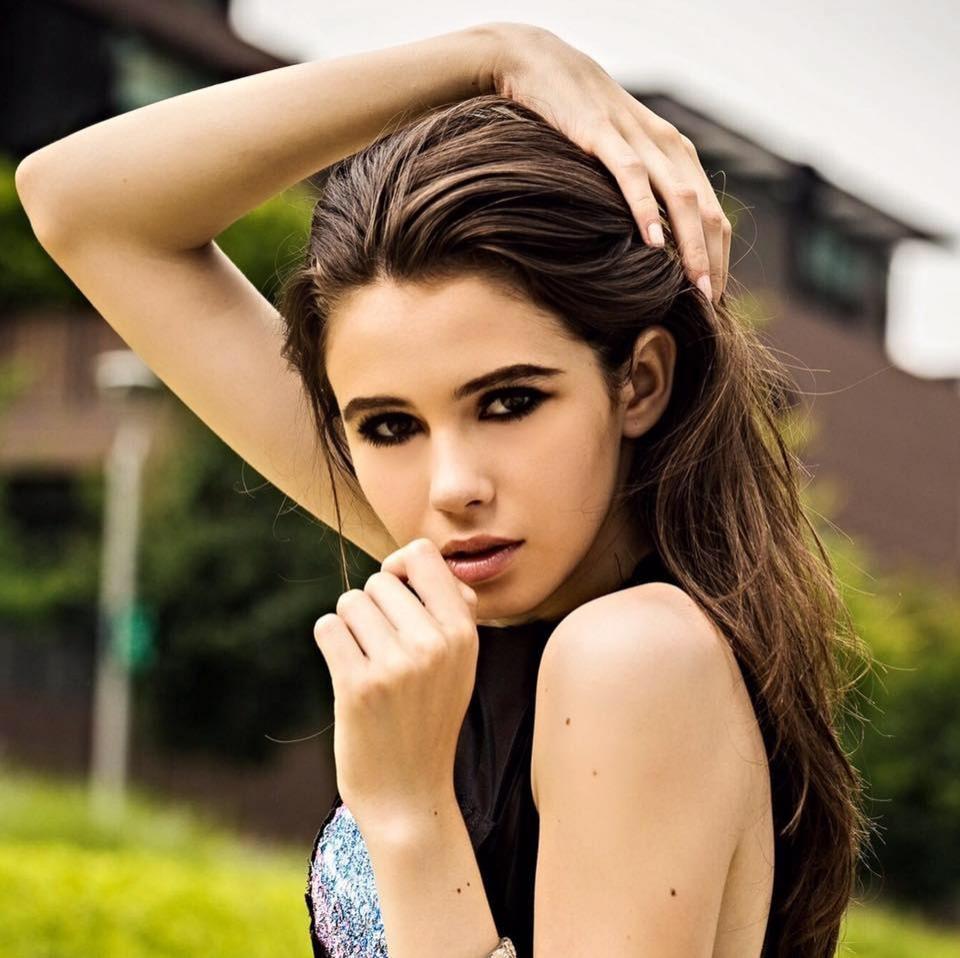 Rebecca Dumitrescu machiată strident, îmbrăcată cu o ținută neagră fără mâneci