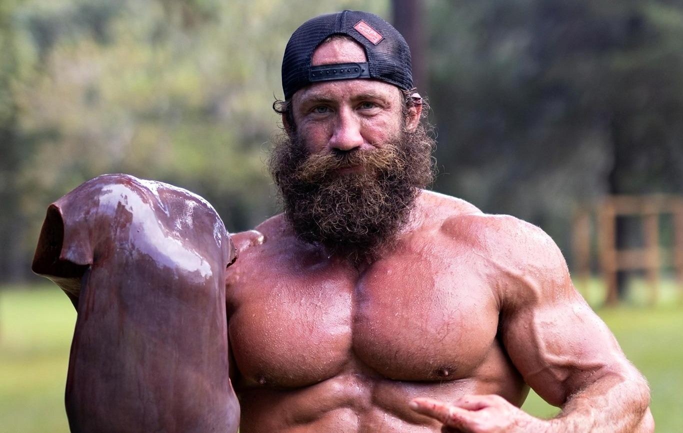 Liver King la bustul gol, ținând o bucată de carne în mână