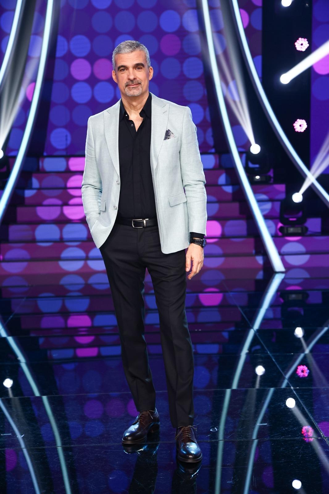 Aurelian Temișan îmbrăcat cu un sacou gri, peste o cămașă neagră