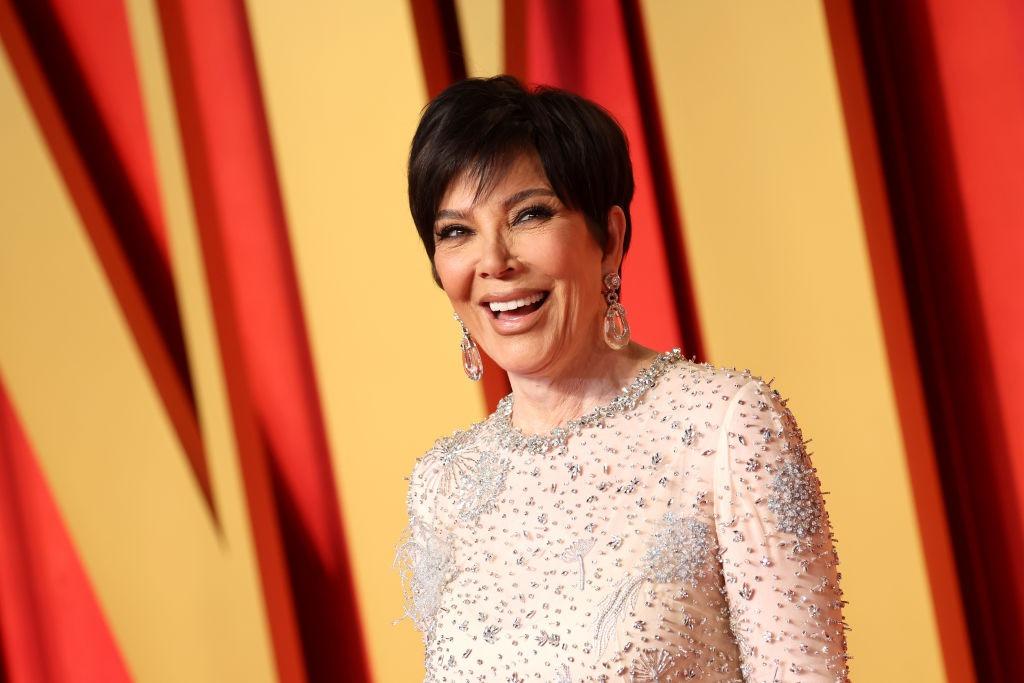 Kris Jenner îmbrăcată cu o rochie bej strălucitoare, accesorizată cu cercei imenși