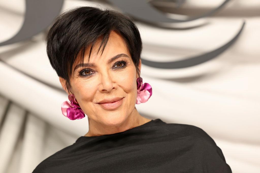 Kris Jenner îmbrăcată cu o rochie neagră, accesorizată cu cercei roz