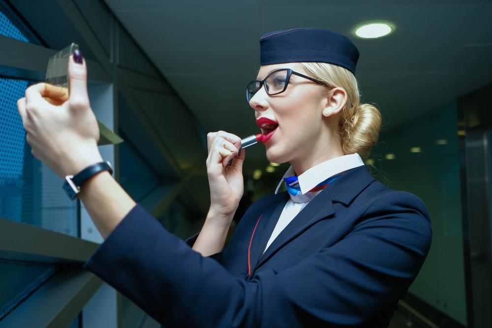 imagine cu o insotitoare de zbor care se da cu ruj rospe buze