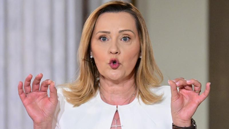 Elena Lasconi îmbrăcată într-o rochie albă gesticulând cu ambele mâini ridicate