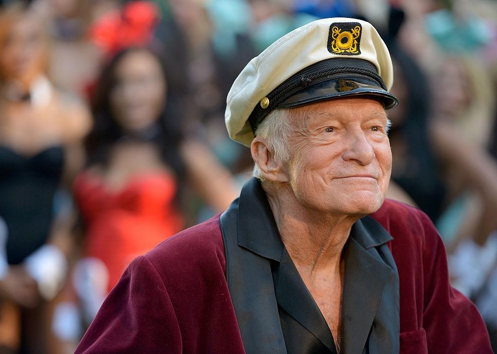 Hugh Hefner îmbrăcat cu un sacou vișiniu, cu revere negre