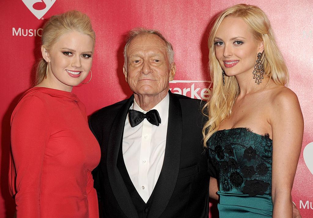 Gemenele Karissa și Kristina Shannon îmbrăcate în rochii elegante alături de Hugh Hefner, îmbrăcat cu un costum negru