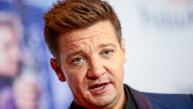 Jeremy Renner îmbrăcat cu un costum bleumarin, vorbind