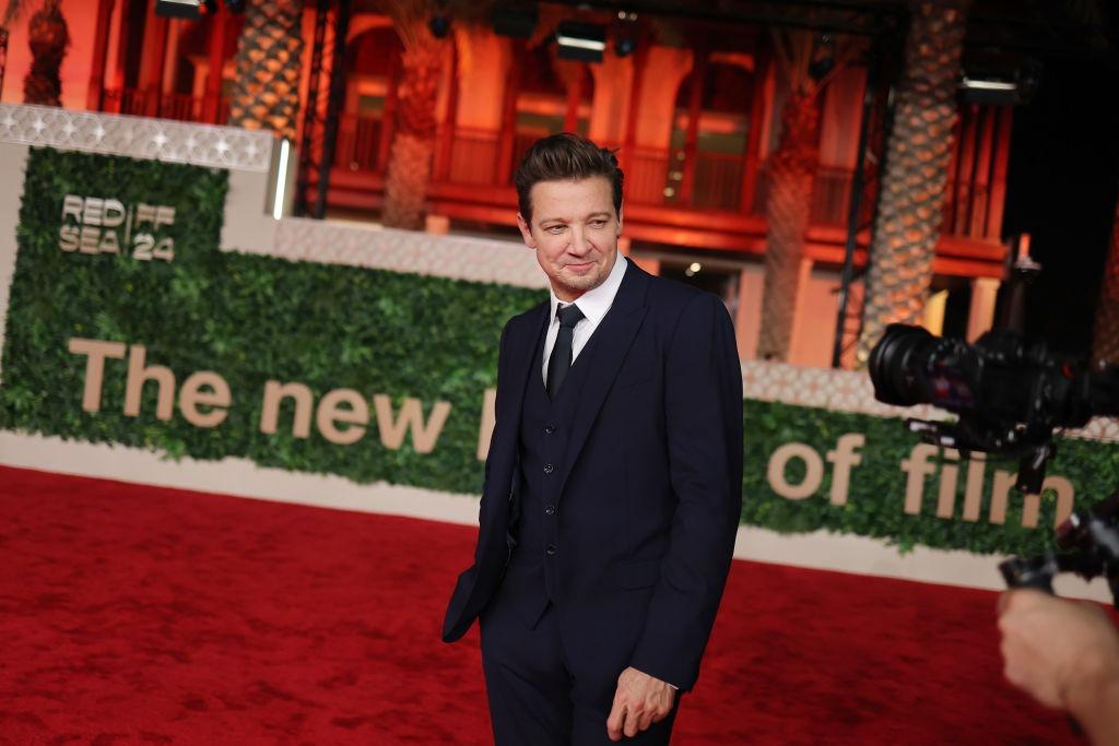 Jeremy Renner îmbrăcat cu un costum bleumarin elegant, la un eveniment