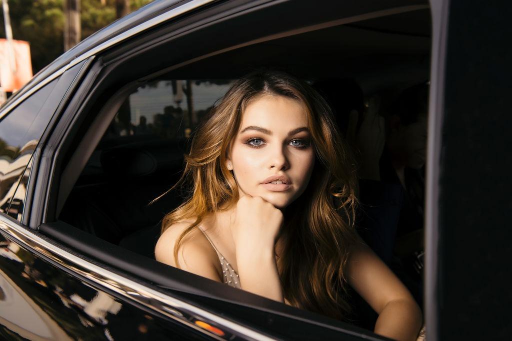 Thylane Blondeau îmbrăcată într-o rochie bej fără mâneci, privind de pe geamul unei mașini