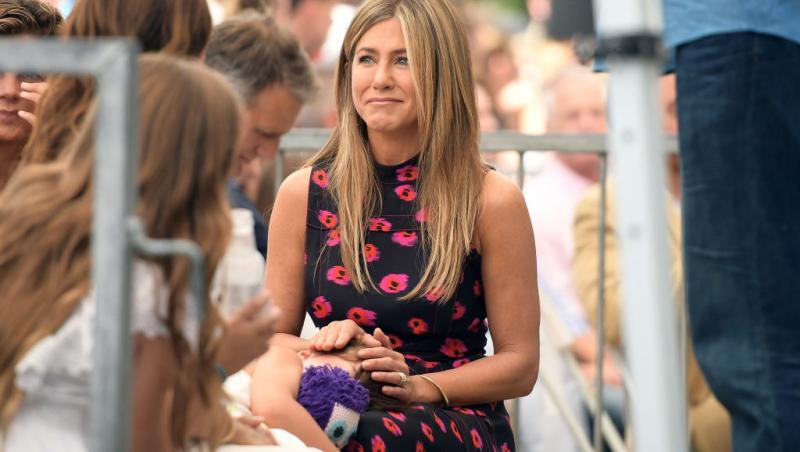 Jennifer Aniston îmbrăcată cu o rochie neagră cu desene florale roșii, mulată