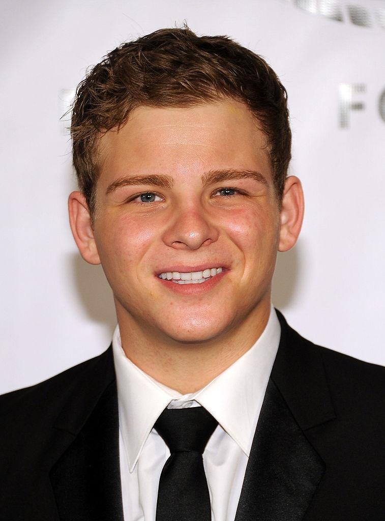 Jonathan Lipnicki îmbrăcat cu un costum negru, peste o cămașă albă
