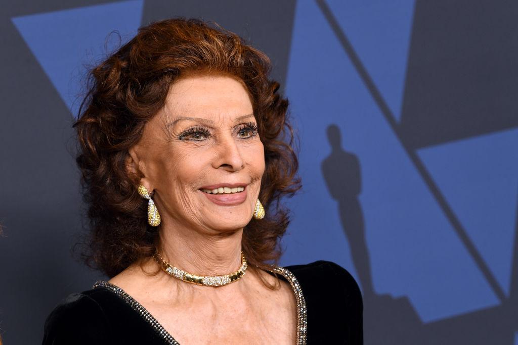Sophia Loren îmbrăcată într-o rochie neagră de catifea, cu accesorii aurii și părul coafat în bucle