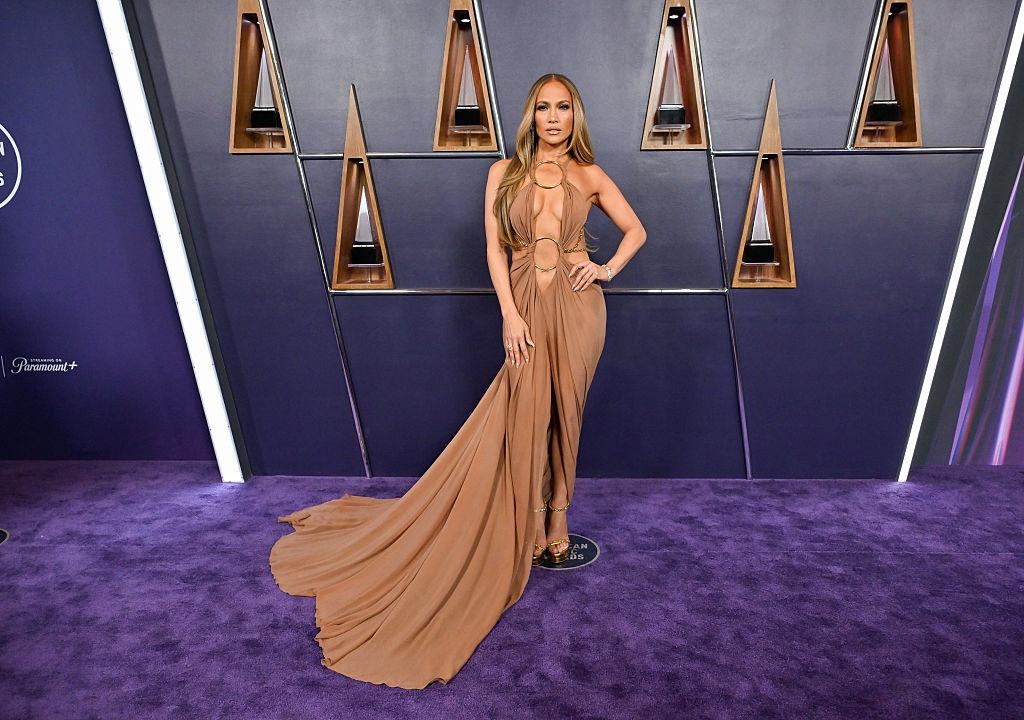 Jennifer Lopez îmbrăcată cu o rochie lungă, maro, extrem de decoltată