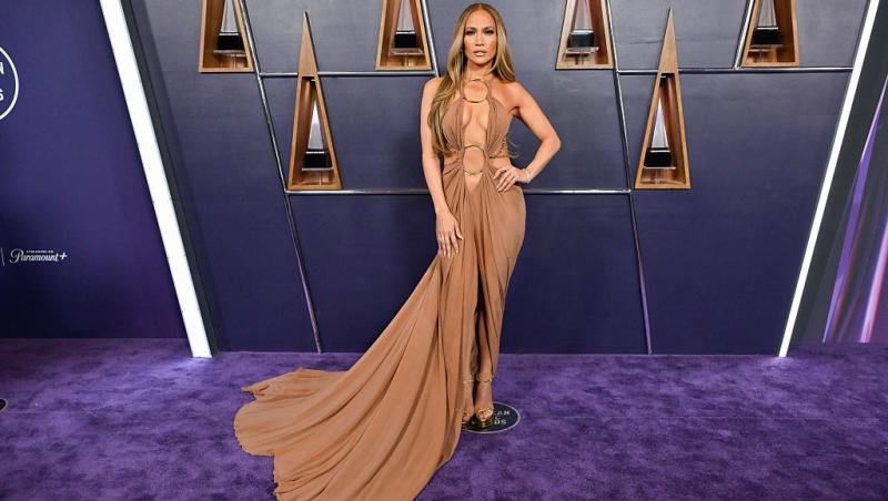 Jennifer Lopez îmbrăcată cu o rochie lungă, maro, extrem de decoltată
