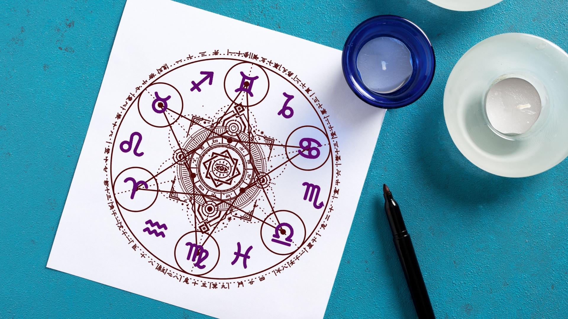 Foaie albă de hârtie cu roata zodiacală, marker și lumânări pe fundal turcoaz reprezentând astrologia