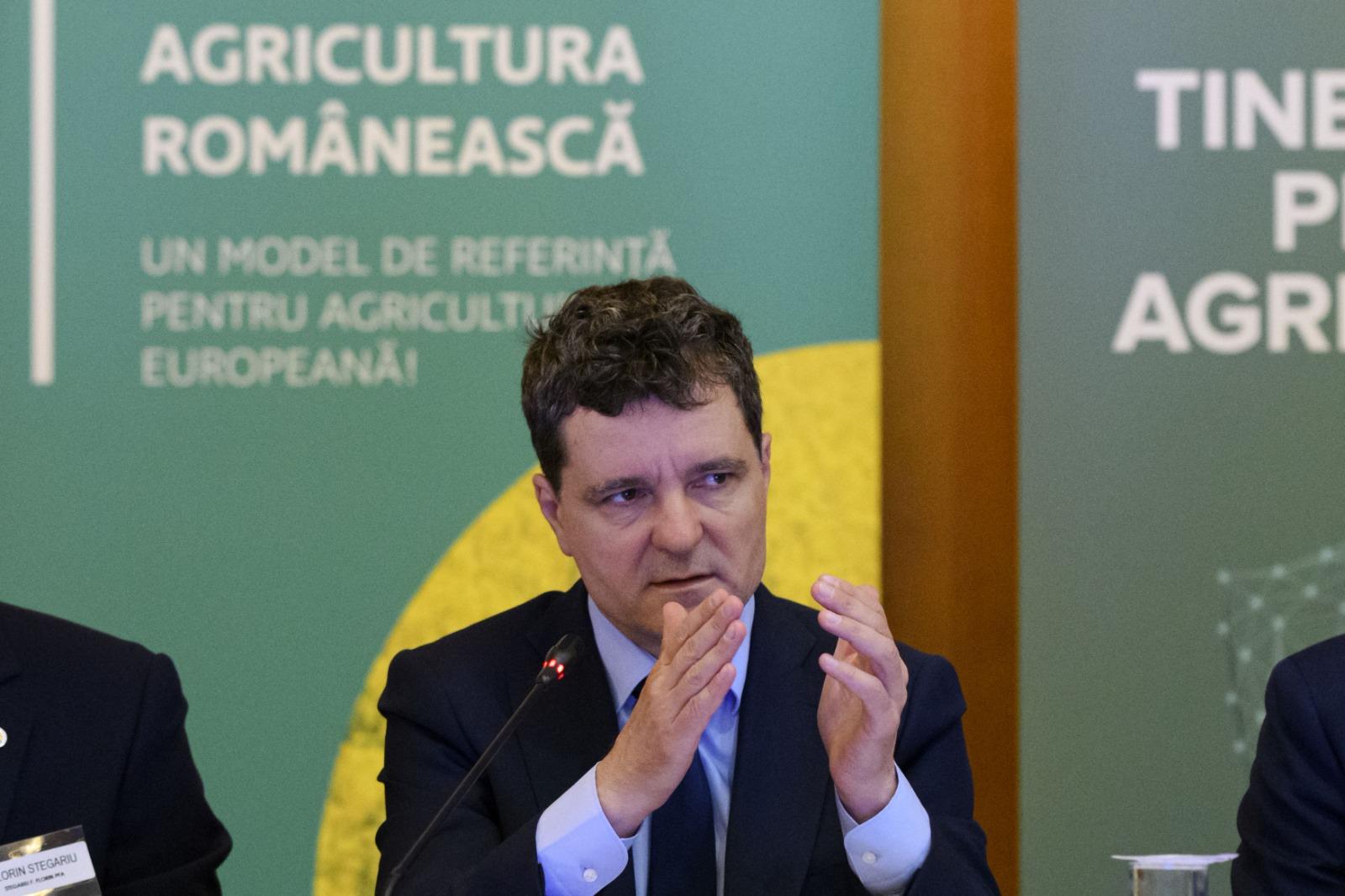 Nicușor Dan îmbrăcat cu un costum negru, vorbind la microfon