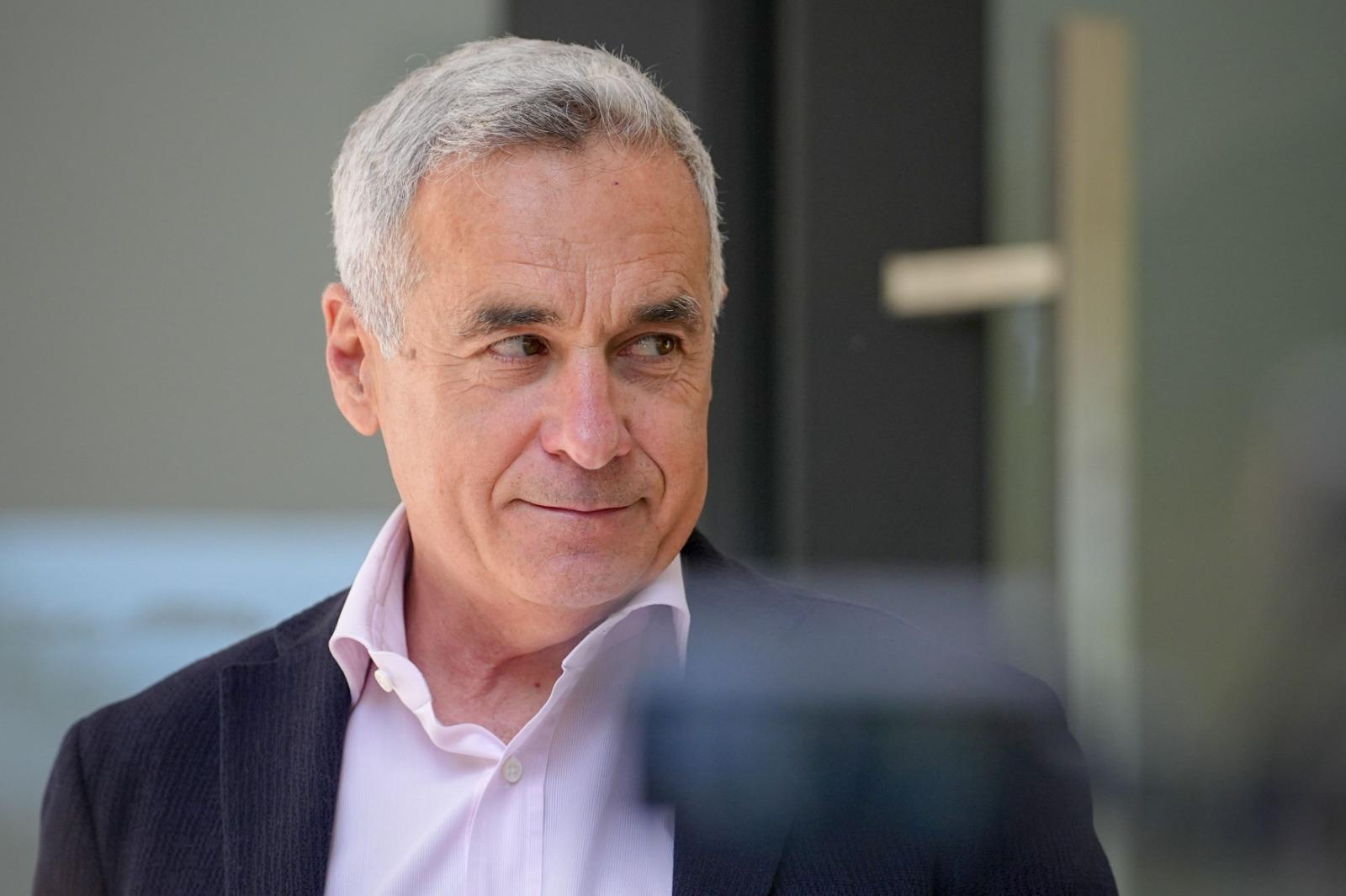 Călin Georgescu îmbrăcat într-un sacou negru, peste o cămașă roz