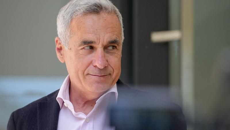 Călin Georgescu îmbrăcat într-un sacou negru, peste o cămașă roz