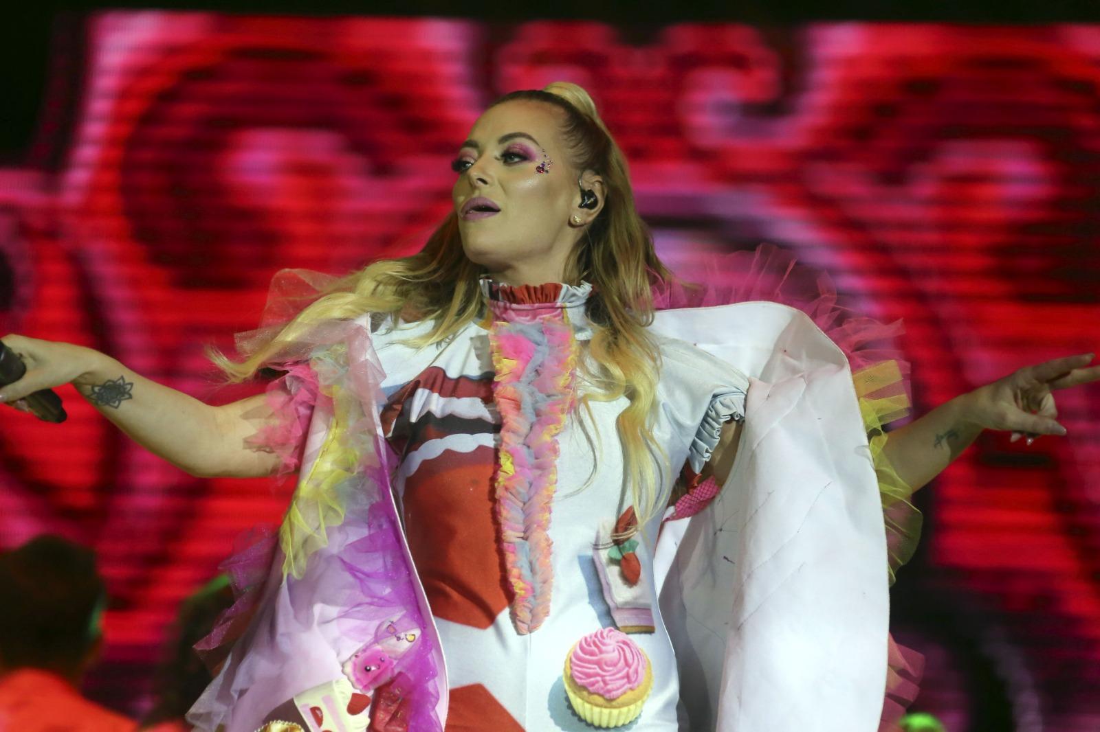 Delia îmbrăcată într-o ținută albă cu detalii colorate, dansând pe scenă