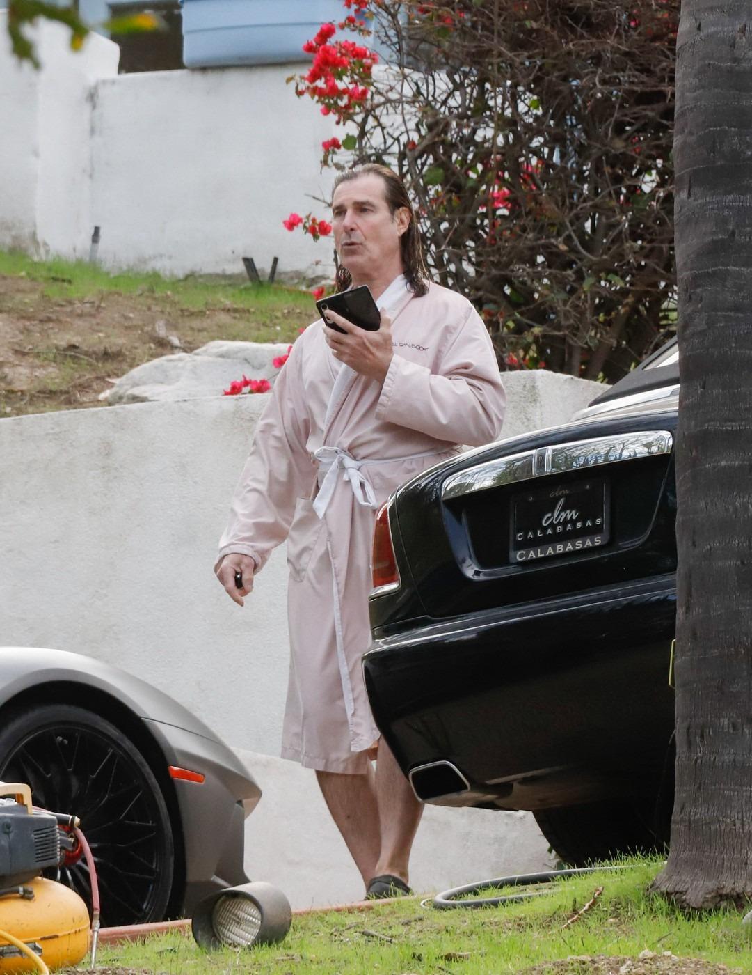 Fabio Lanzoni îmbrăcat cu un halat roz, mergând și vorbind la telefon