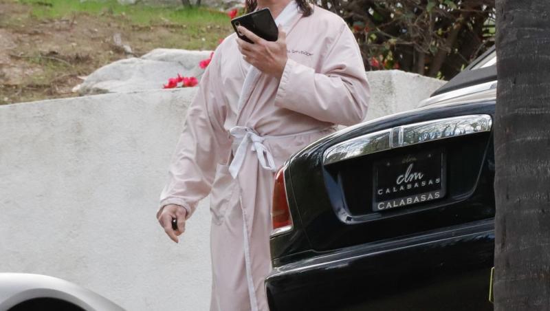 Fabio Lanzoni îmbrăcat cu un halat roz, mergând și vorbind la telefon