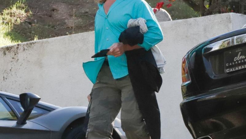 Fabio Lanzoni îmbrăcat cu o cămașă bleu și pantaloni kaki, mergând și vorbind la telefon