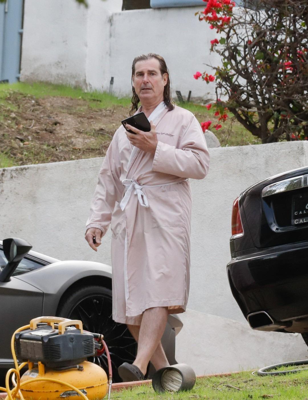 Fabio Lanzoni îmbrăcat cu un halat roz, mergând și vorbind la telefon