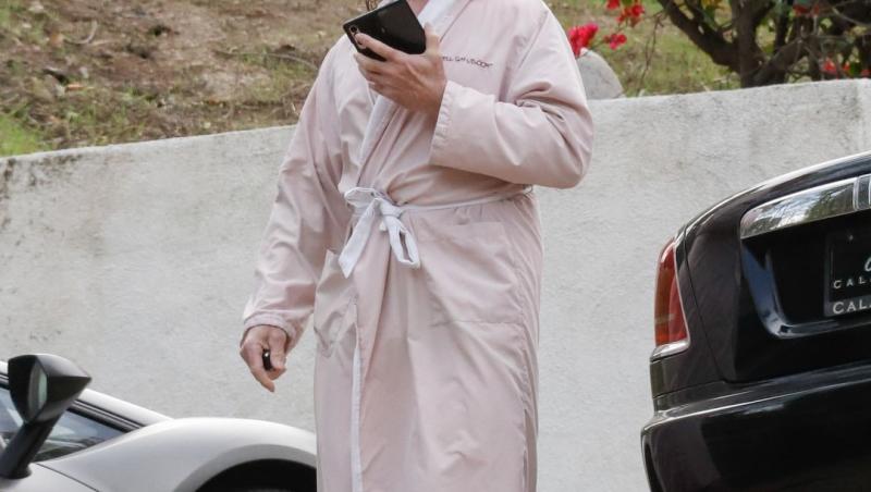 Fabio Lanzoni îmbrăcat cu un halat roz, mergând și vorbind la telefon