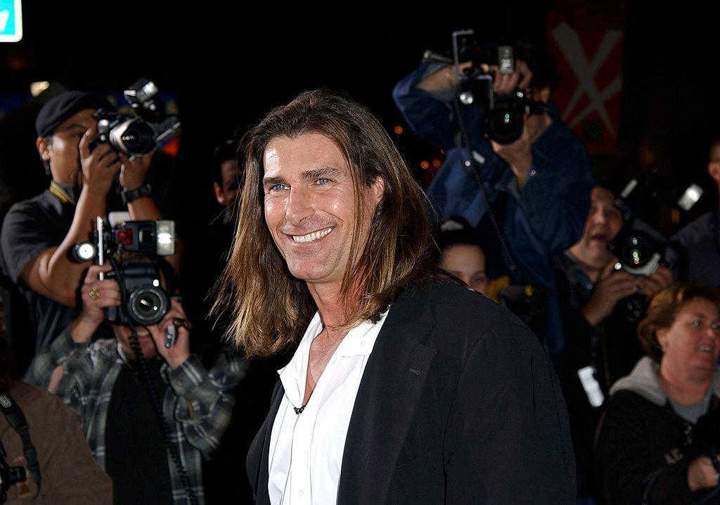 Fabio Lanzoni îmbrăcat cu un sacou negru peste o cămașă albă, zâmbind