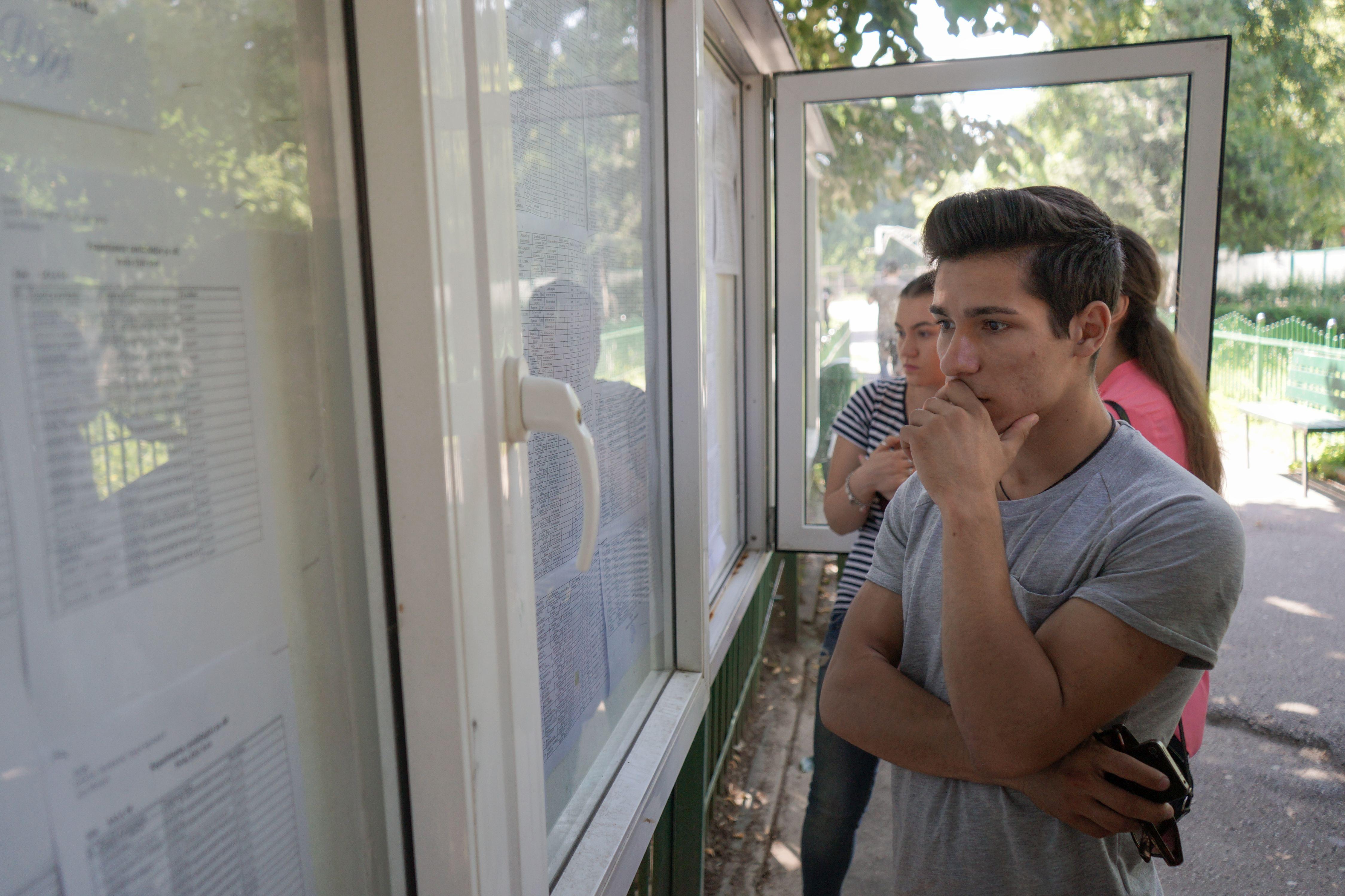 imagine cu un tanar care priveste catre panoul cu notele la bacalaureat