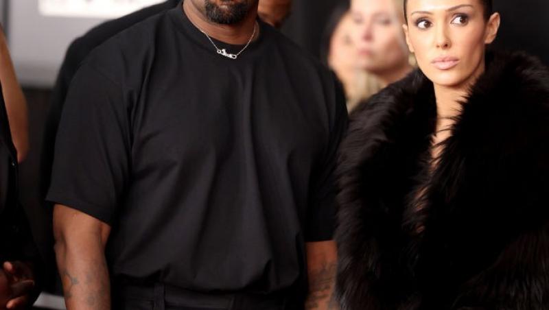 Bianca Censori îmbrăcată cu o haină neagră pufoasă, alături de Kanye West, îmbrăcat în negru